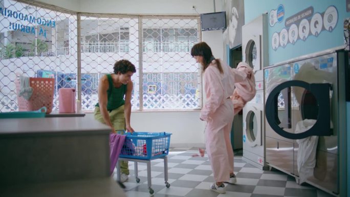 嬉闹的情侣在自助洗衣店闲逛。有趣的朋友洗衣服