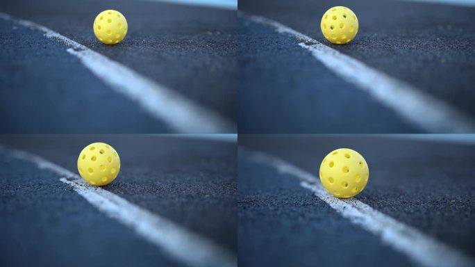 在球场上以慢动作滚动的匹克球用的带孔塑料球