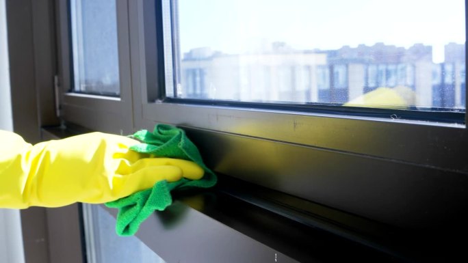 人，家务和持家观念——女人戴着手套，用抹布和清洁剂在家里喷擦窗户