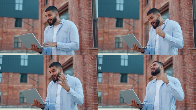 留着胡子的印度男性站在户外，手里拿着便携式笔记本电脑，在网上阅读铺天盖地的新闻。穿着便装的男人兴奋地