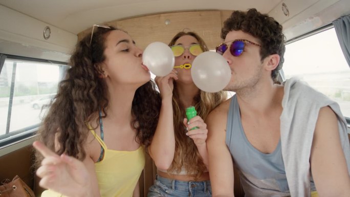 美丽的青少年潮朋友吹肥皂泡在节日在露营车在公路旅行冒险