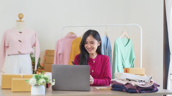 快乐的年轻女商人在家里用笔记本电脑处理网上购物订单。微笑的时尚零售店主在网站上与顾客交流经营理念