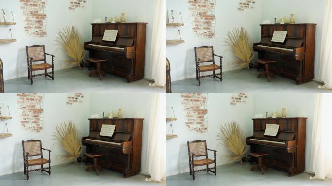 在一个房间里，一张小椅子旁边的白砖墙背景上有一架旧钢琴。作曲家的房间