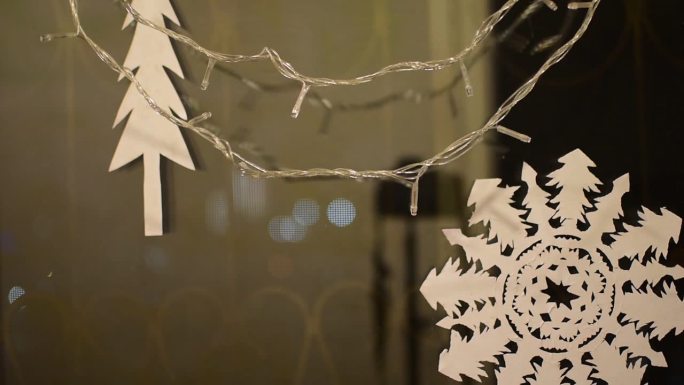 雪花和圣诞树剪纸，在窗户上挂着闪闪发光的花环