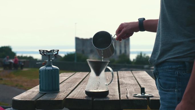 在露营环境中制作过滤咖啡，Сlose在玻璃咖啡机中倒入咖啡的水的镜头