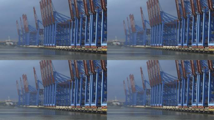 汉堡港Burchardkai的蓝色和红色龙门吊在乌云和特殊的光线下。