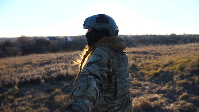 跟随我拍摄的年轻女兵在日落时分牵着男性的手慢跑穿过田野。欢快的女兵拉着她的男朋友在草地上走。快乐的军