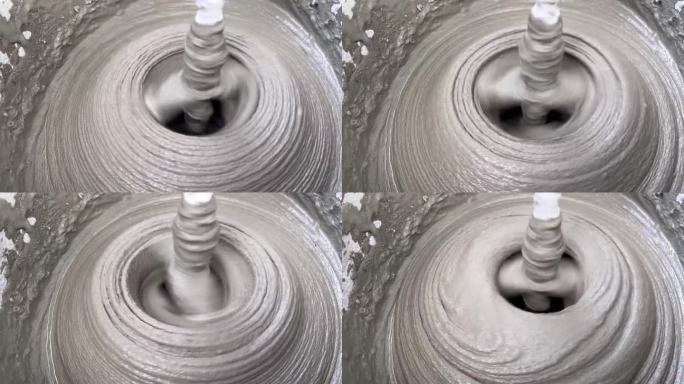 用搅拌器在桶中搅拌水泥砂浆的特写，混合砂浆的纹理。施工混合料的制备。