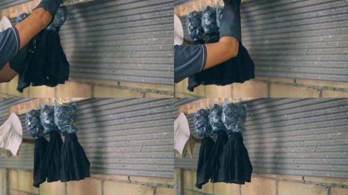 不被认出的人戴着橡胶手套，用手把染好的衣服挂在木架上，当地纺织业的传统是用深蓝色颜料染色和晾晒衣服