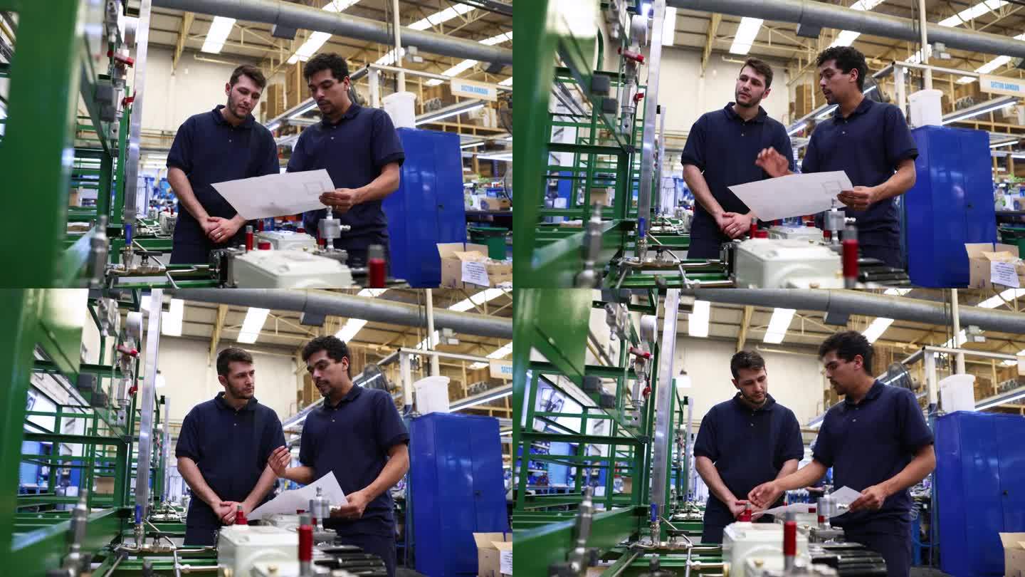 一位男同事在一家水泵厂培训一位新员工，一边拿着机器的蓝图，一边向他解释整个过程