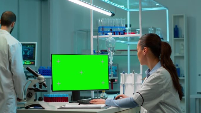 科学家们坐在办公桌前，用仿真屏幕在个人电脑上工作