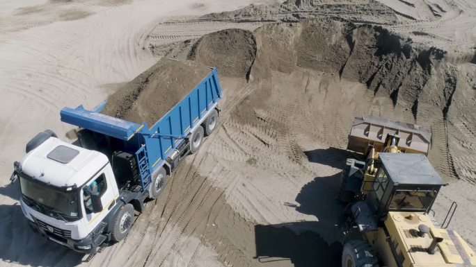 满满一卡车的土。现场。建筑工地上装土的自卸卡车的俯视图。建筑工地或采石场的自卸卡车装满了土