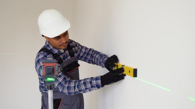 印度工人在建筑工地用激光找平仪测量墙壁