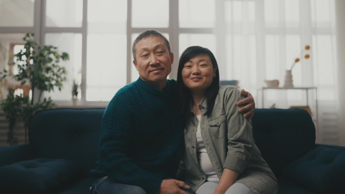 快乐的亚洲老人拥抱他的成年女儿，温暖的家庭关系