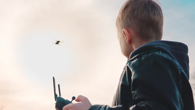 快乐的男孩在大自然中玩无人机。孩子用遥控器控制无人机。