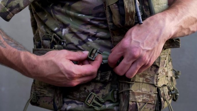 身着战斗迷彩服的乌克兰军人系紧他的防弹背心，近距离拍摄