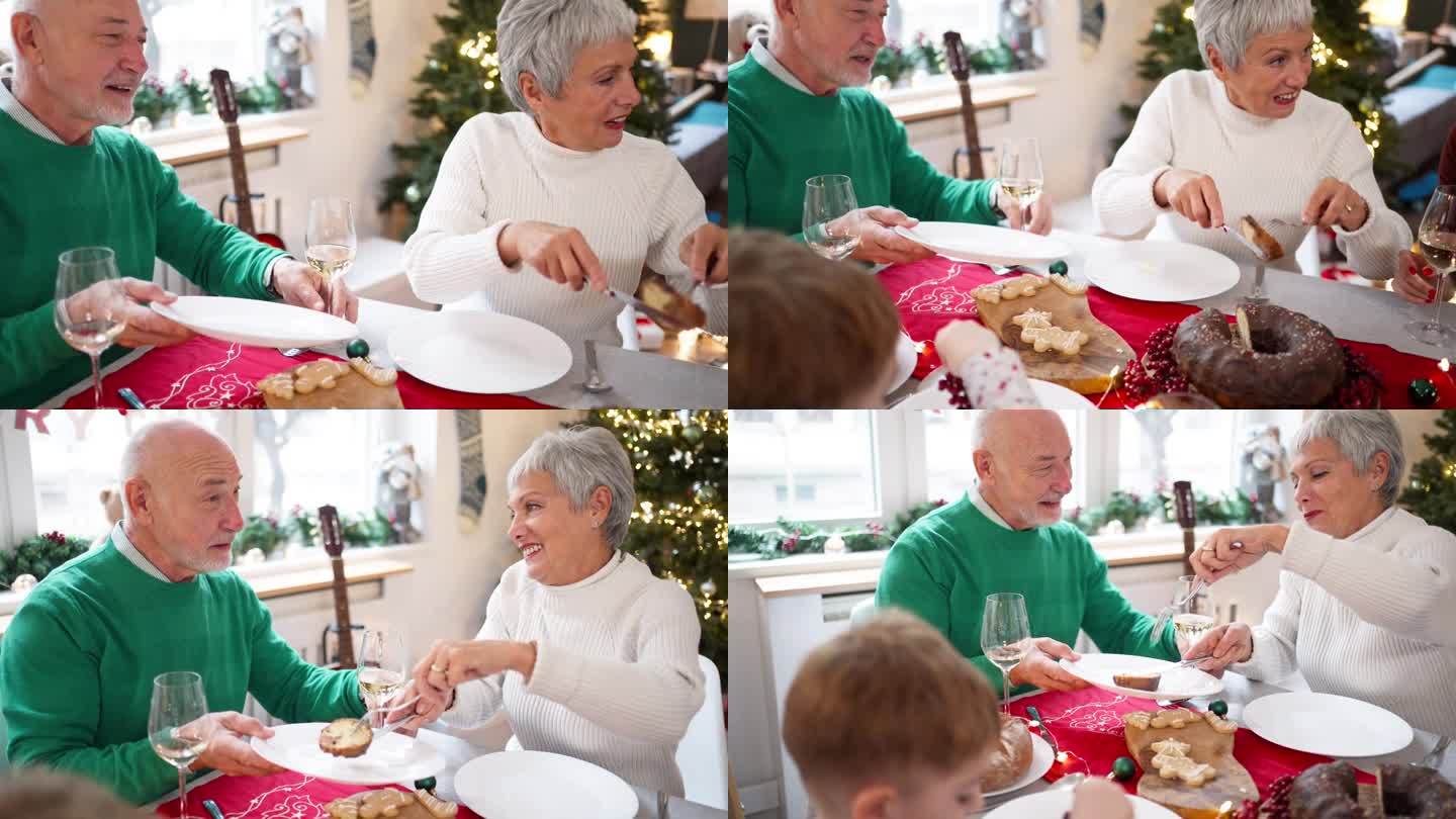 一对年长的白人夫妇在家庭圣诞午餐时分享一个面包蛋糕