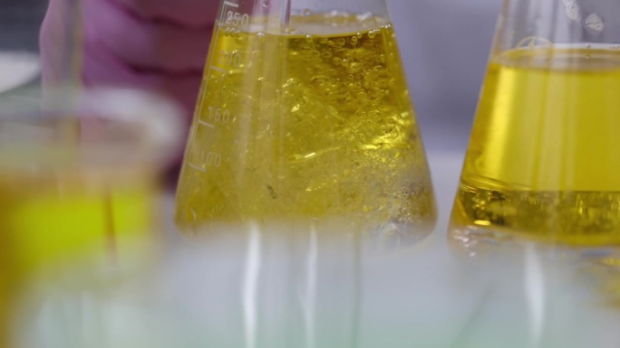 科学家化学家在实验室用机油将液体倒入烧瓶中，特写4k电影慢动作