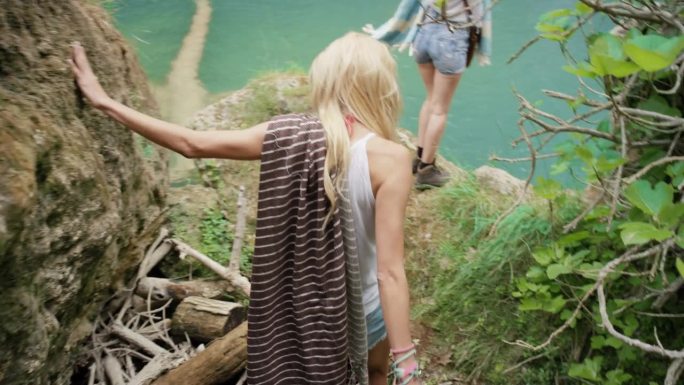 年轻女子发现隐藏瀑布的秘密举起双臂庆祝在自然池塘里的野生游泳冒险最好的朋友，在大自然中享受无忧无虑的