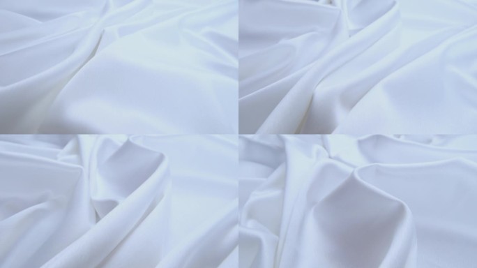 闪亮的白色流动的布料纹理拍摄近距离观察微距镜头。波浪形干净的丝织材料。纺织缎面抽象背景。床单、窗帘及
