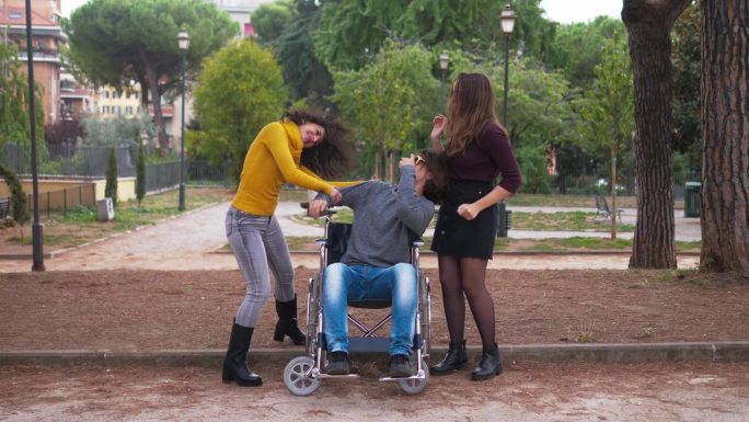 轮椅使用者跳舞——一个年轻的截瘫男子用智能手机听音乐，和他的朋友们一起跳舞