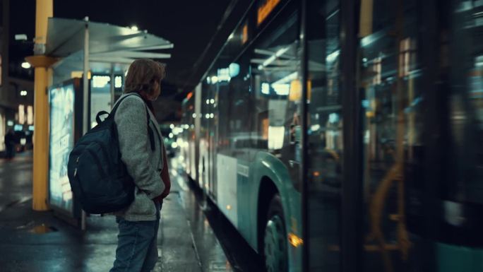 成熟的商人背着双肩包走在夜晚的城市公交车上