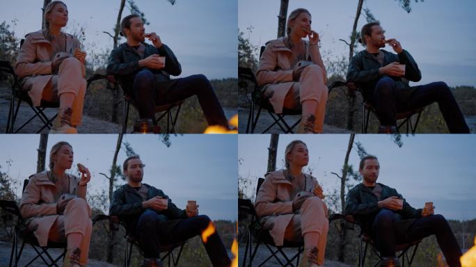 运动夫妇坐在大自然的火堆旁吃晚餐