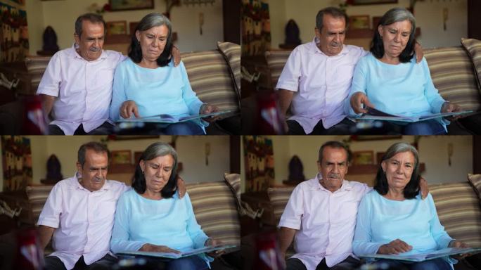 一对老年夫妇坐在客厅的沙发上看相册的照片