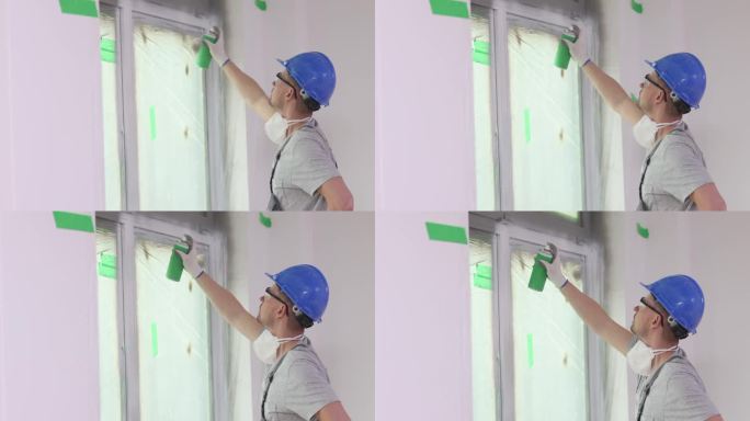 建筑工人正在用白色喷漆粉刷窗户开口