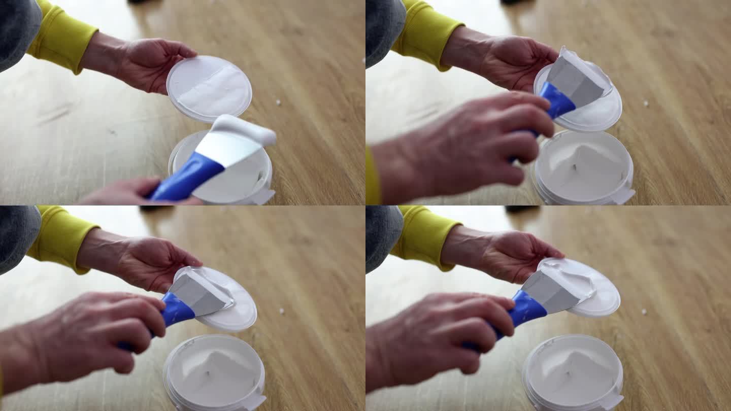 大师级修理工用抹刀从塑料罐中取出油灰