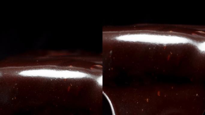 垂直视频。随着一滴黑巧克力从巧克力棒上滴下来而向下移动，特写。