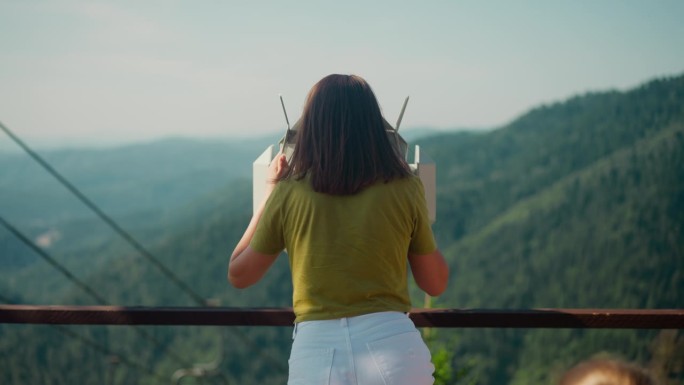 女人站在山顶上用双筒望远镜眺望