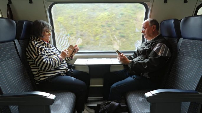 老年夫妇在火车上玩智能手机