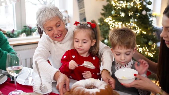 在家庭圣诞午餐期间，孩子们用糖粉装饰蛋糕