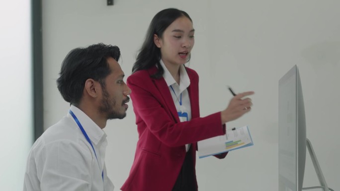 经理导师与年轻的亚洲女同事交谈，在会议上展示在线项目成果。两个快乐多样的专业高管团队在办公室工作，使