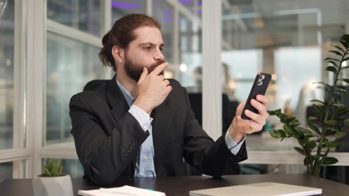 一名员工试图在个人办公桌上用现代智能手机上网，这让他感到惊讶。工作勤奋的男性经理，需要稳定的人际网络