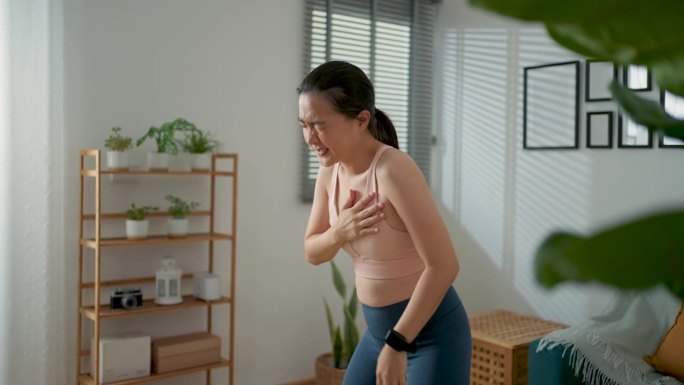 一名亚洲女性在家里客厅运动时胸口疼痛。