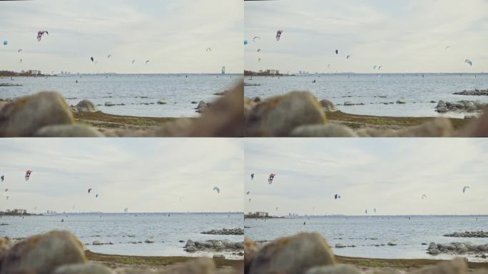 慢动作镜头捕捉到熟练的风筝冲浪者在爱沙尼亚风景如画的北欧海岸线上滑翔，远处的背景是首都塔林的标志性轮