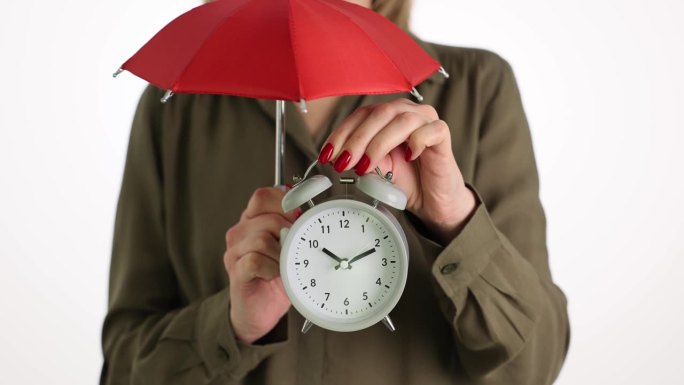 女人拿着闹钟和红伞