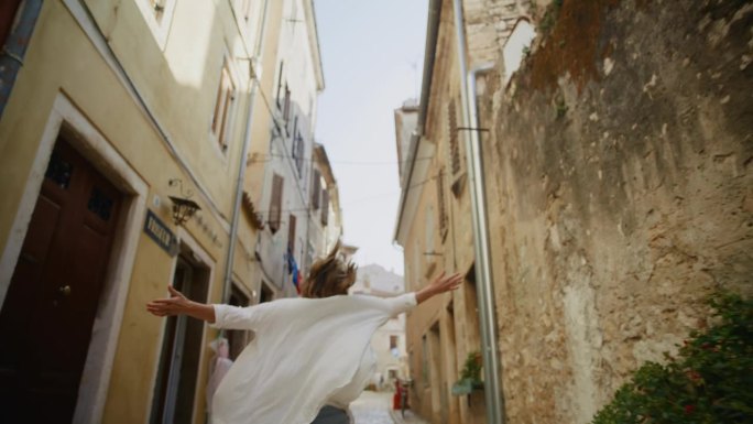 SLO MO微风般的幸福:在罗维尼的永恒小巷里，女人张开双臂快乐地奔跑