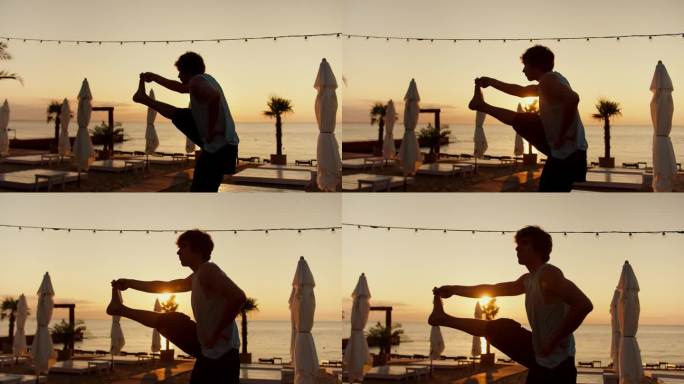 在一个阳光明媚的早晨，一个年轻人抬起腿伸了个懒腰。早上在阳光海滩做运动和瑜伽。健康的生活方式