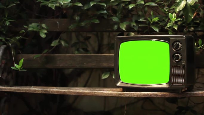 在一个城市公园里，复古电视打开了带有彩色条的绿屏。近距离，4K分辨率。
