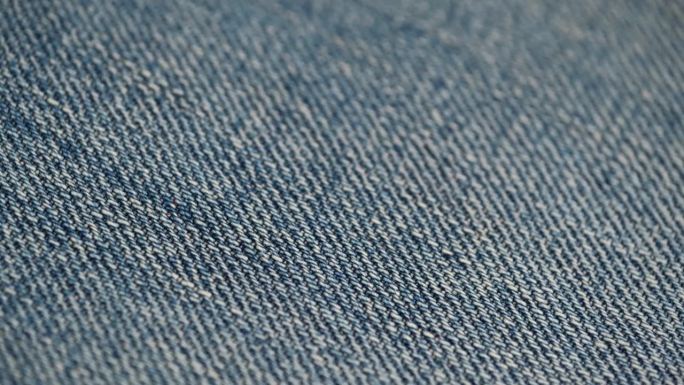 宏观视频旋转蓝色牛仔裤的天然纺织品。牛仔面料的特写质感。前视图。