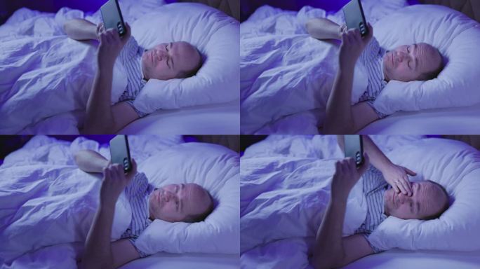 中年秃顶男子躺在床上玩手机