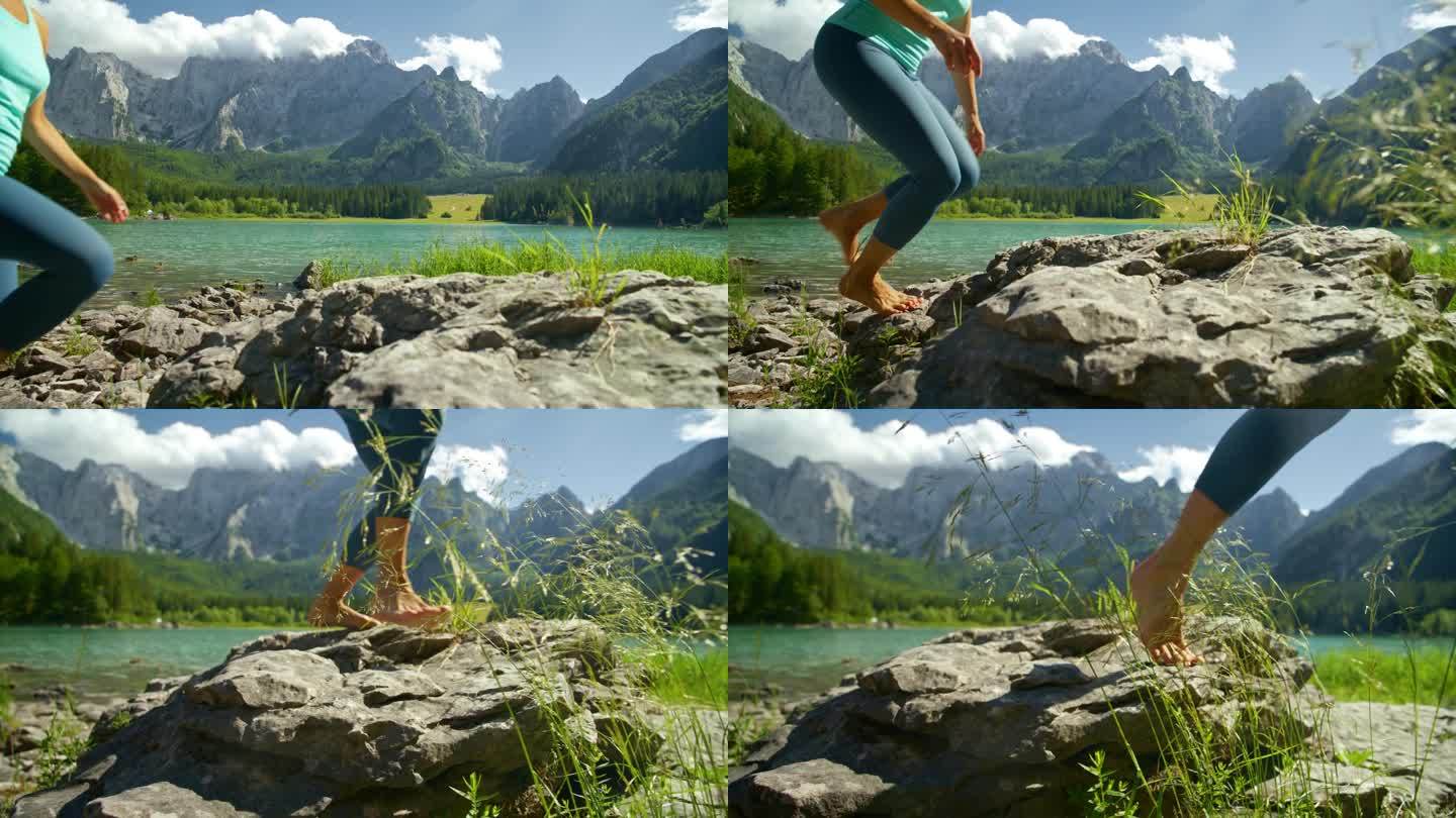 赤脚女人沿着阳光明媚的山间湖泊踩在岩石上