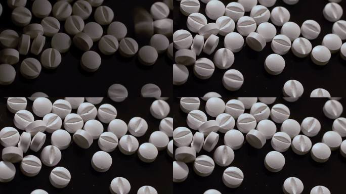 一堆白色药片散落在黑色表面，美国阿片类药物危机。