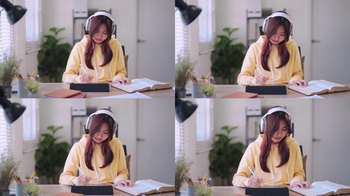 图为，一名亚洲女学生正在认真地阅读教材，并在书桌前的平板电脑上做总结