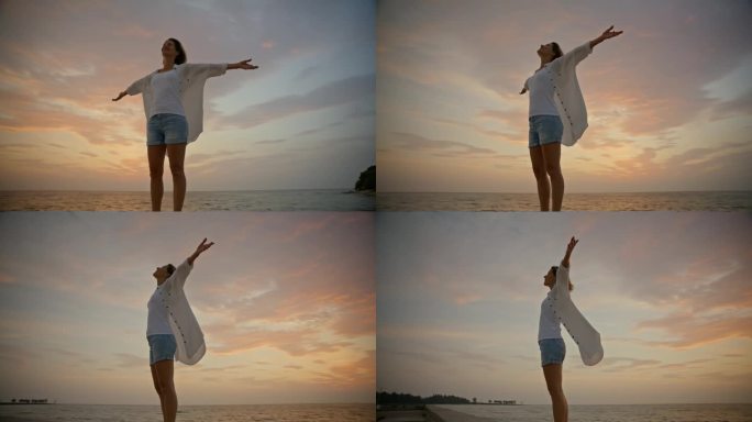 一个光芒四射的慢镜头，一个女人站在夕阳的天空下，她的手臂伸展在纯粹的幸福中。傍晚云彩的鲜艳色调为她的