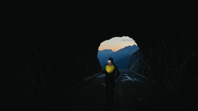 女子带着头灯在黑暗的山间隧道里慢跑