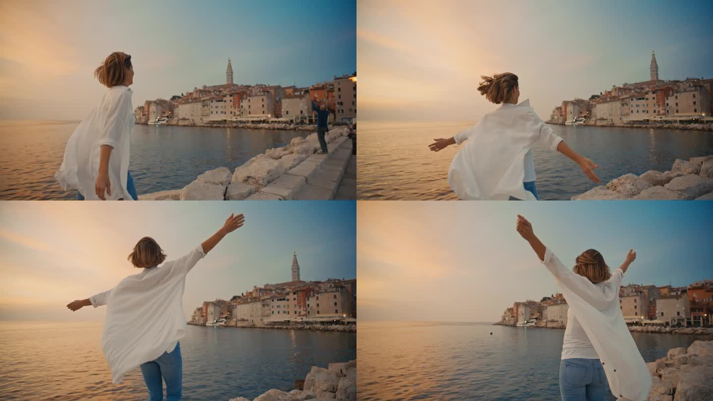 享受日落的喜悦:一名女子在罗维尼的一个码头上奔跑，她张开双臂，露出幸福的表情